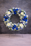 Coroană funerară premium cu trandafiri albaștri și albi, simbol al respectului și liniștii, ideală pentru ceremonii funerare.
